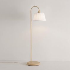 a floor lamp with a white shade on the base and a light bulb attached to it