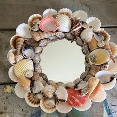 a wreath made out of seashells on top of a wooden table next to a mirror