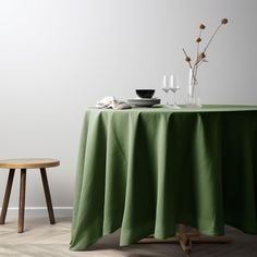 a table with a green cloth on it next to a small wooden stool and vase