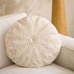 a white round pillow sitting on top of a couch