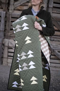 a woman is holding a quilt in her hands