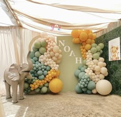 an elephant stands in front of a backdrop made out of balloons and greenery with the word noah on it