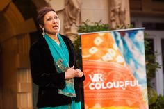 a woman standing in front of a colorful sign