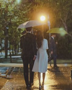 two people walking in the rain under an umbrella