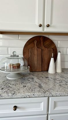 a kitchen counter with white cabinets and wooden cutting board