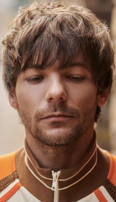 a close up of a man with his eyes closed wearing a cross necklace and looking at the camera