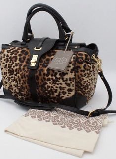 Stand out in the crowd with this stunning RAFE NEW YORK Bryn satchel/cross-body/shoulder bag. The leopard pattern in black makes a bold statement and is complemented by gold hardware on the flap with a turn knob closure. The bag is made of genuine Italian calf hair body with black leather accents, giving it a luxurious feel. Measuring 10.5" in height, 12" in width, and 5" in depth, this bag is the perfect size for everyday use. The interior lining is black and features enough space for all your essentials. With its versatile style, this bag can be worn as a satchel, cross-body, or shoulder bag, making it a must-have addition to any wardrobe. Christian Bracelets, Hello Lover, People Clothes, Animal Fur, The Leopard, Leather Accents, Leopard Animal, Shopping Ideas, Leopard Pattern