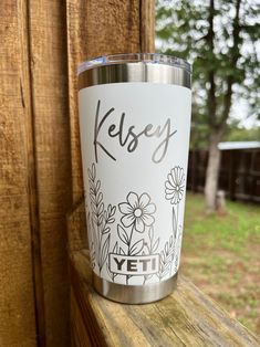 a yeti cup sitting on top of a wooden window sill next to a fence