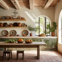 a dining room table with plates and bowls on it next to an arched window that overlooks the outside