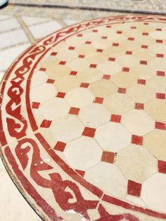 a red and white patterned table top on a tiled floor