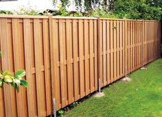 a large wooden fence next to a lush green yard