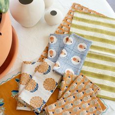 several napkins are laying on a table next to a potted plant and an egg