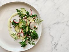 a white plate topped with cucumbers, radishes and other veggies