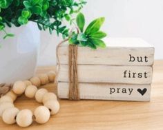 a potted plant sitting next to two wooden blocks that say but first, pray