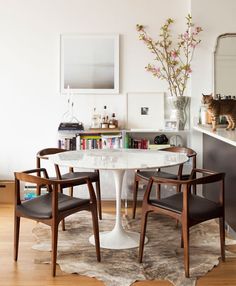 a cat sitting on top of a table next to two chairs