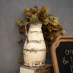 a white vase sitting on top of books next to a chalkboard