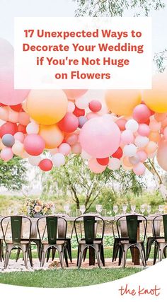 a bunch of balloons that are in the air over some chairs and tables with flowers on them