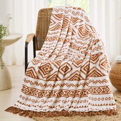 an orange and white blanket sitting on top of a chair next to a wicker basket