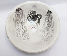 a bowl shaped sink with black and white designs on the bottom, in front of a white background