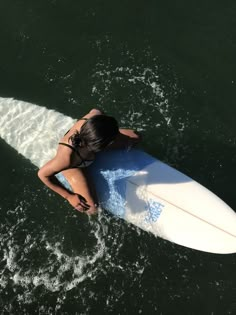 a woman riding on top of a white surfboard in the middle of the ocean