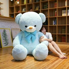 a woman sitting on the floor next to a large teddy bear