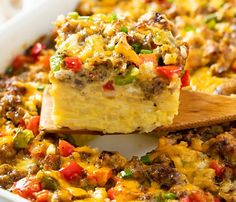 a casserole dish with sausage, peppers and cheese in it on a wooden spoon