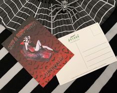 there is a spider web on the table next to an envelope and postcard that says happy halloween