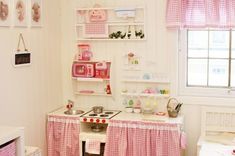 a pink and white play kitchen in a child's room