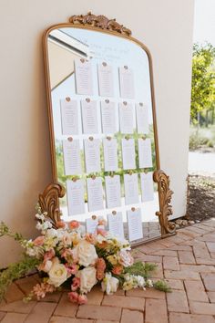 a mirror sitting on top of a brick floor next to a table with flowers and seating cards