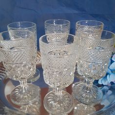 four glass goblets are sitting on a tray with blue flowers in the background