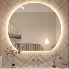 a bathroom with a large round mirror on the wall above it and flowers in vases