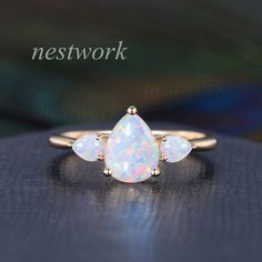 an opal ring with three pear shaped diamonds