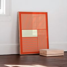 an orange frame sitting on top of a hard wood floor next to a wooden box