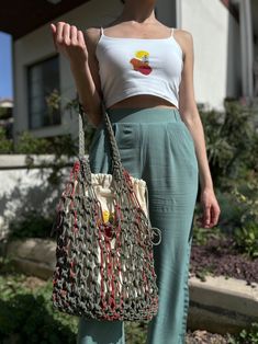 a woman carrying a purse in front of a house with her hand on her hip