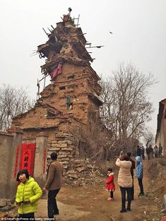 people are standing in front of an old building that has been torn down and is surrounded by debris