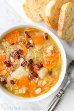 a bowl of soup with carrots, beans and bread