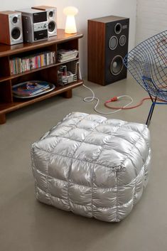 an inflatable mattress is sitting on the floor next to speakers and bookshelves