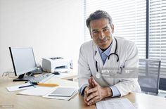 a male doctor sitting at a desk with his arms crossed and looking off to the side