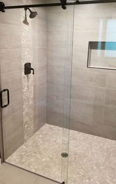 a walk in shower sitting next to a white tiled wall and floor with glass doors