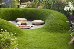 a garden with green grass and rocks in the center, surrounded by flowers and plants