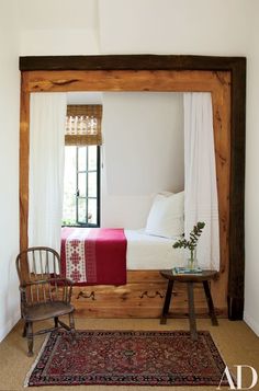 a bed sitting under a window next to a wooden frame