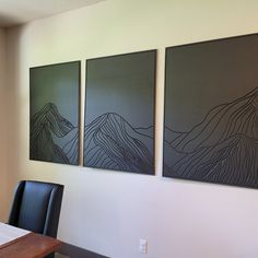 three paintings on the wall above a dining room table