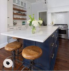 two stools sit in front of an island with white countertops and blue cabinets