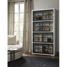 a white bookcase with glass doors in front of a window