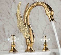 a golden faucet with two crystal balls on the side and an angel - like handle