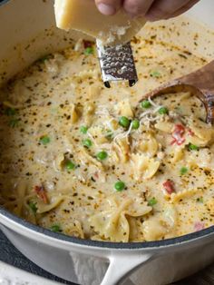 a ladle scooping cheese out of a pot filled with macaroni and cheese