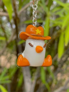 an orange and white bird with a hat on it's head hanging from a chain