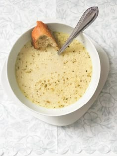 a white bowl filled with soup and a piece of bread sticking out of the top