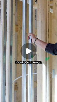 a man standing in the middle of a room that is being built with wooden framing