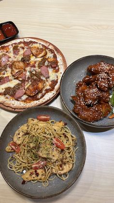 three plates with different types of food and sauces on them, along with two pizzas